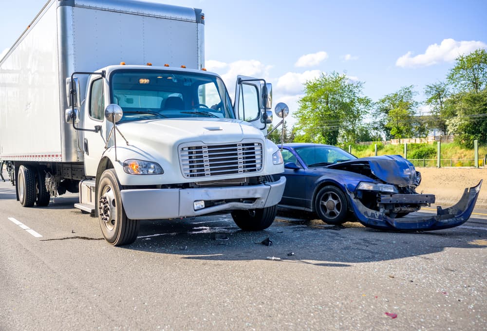 A damaged car and truck after a collision on a sunny day road.